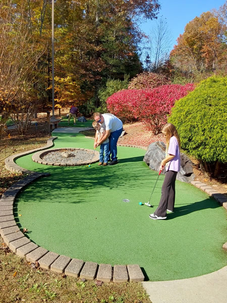 father and kids playing mini golf